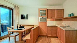 A compact kitchen with wooden cabinets, a built-in oven, and a dining area with a bench.