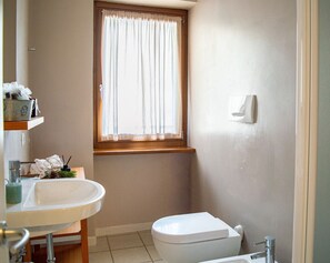 Une salle de bain avec un lavabo, des toilettes et une fenêtre.