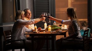 A family dining at a table with candles, a bottle, and a glass of red wine. - Casa al Moro 5 (Rocca Pietore)