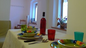 A dining area with a table set for four, featuring colorful plates and a red wine bottle.