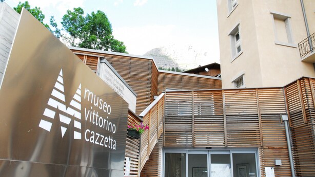 A building with a modern facade, wooden slats, and a sign for 'museo vittorini cazzetta'.