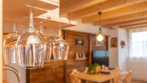 A wooden interior with hanging wine glasses and a dining area. - Chalet Laura (Alleghe)