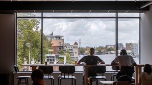 Interieur van een restaurant met grote ramen met uitzicht op een stadsgezicht.