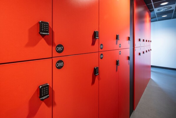 A row of red lockers with numbered keys, each with a keypad lock.