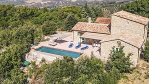 A stone villa with a swimming pool and lounge chairs. - Villa with garden, private pool and air conditioning. Panoramic views!! (Umbria)