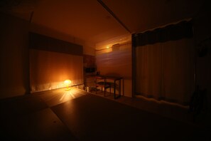 A dimly lit room with a single table and chair, a lamp, and a curtain. - Seaside Harbor Odawara (Odawara)