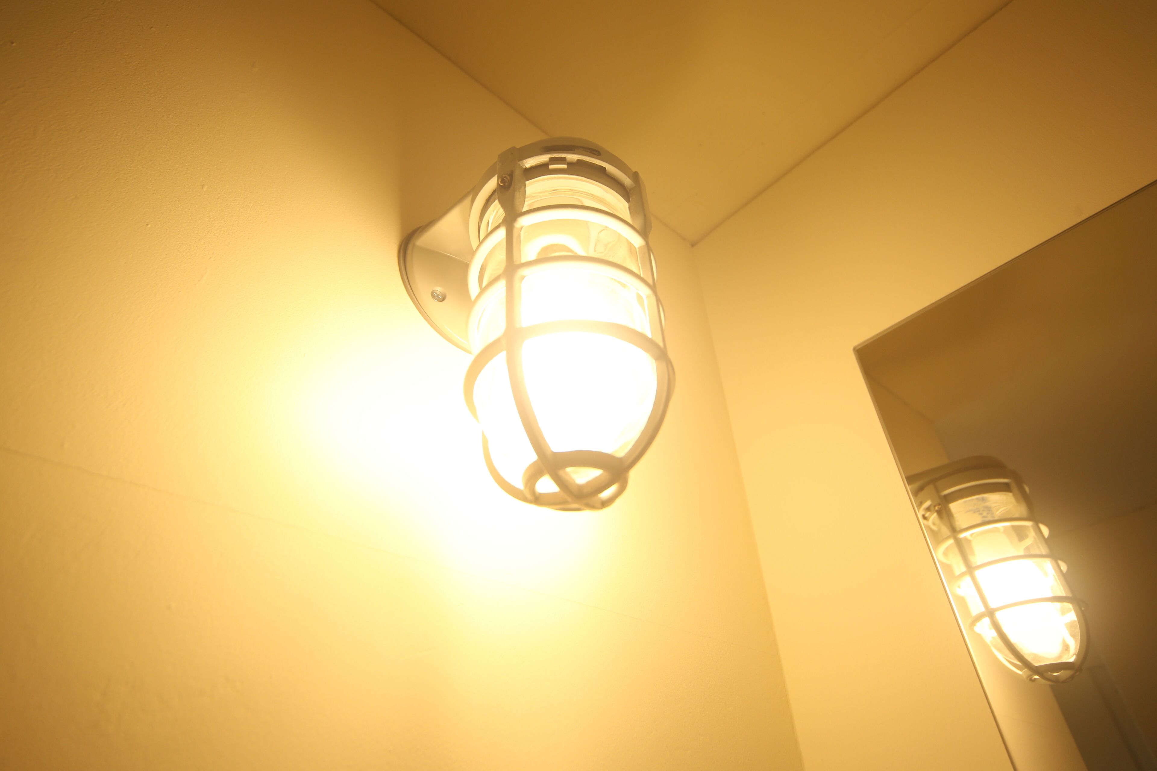 A wall-mounted light fixture with a cylindrical design and a visible electrical cord.