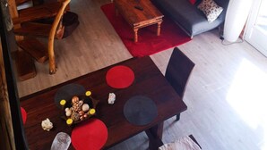 Een gezellig interieur van een blokhut met een vide, een bank en een eettafel met een rood-grijze tafelkleed.