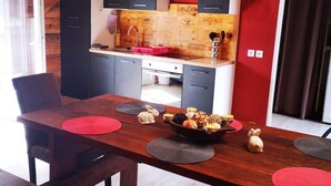 Een moderne keuken met donkere kastjes, een houten aanrechtblad en een rode muur.