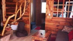 Een gezellig houten blokhut interieur met een houten eettafel, een bank en een rode vloerkleed.