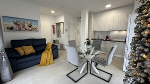 A modern living room with a dark blue sofa, a glass dining table, and a Christmas tree. - Penthouse El Carmelo New, Modernly Furnished with Huge Terrace < 50m from Beach (Caleta de Vélez)