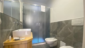 A modern bathroom with a wooden vanity, a white sink, a bidet, and a toilet.