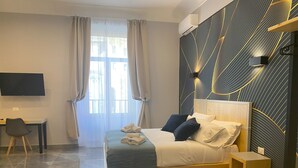 A modern hotel room with a large bed, a desk, and a TV.