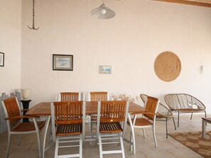 Un coin repas avec une table et des chaises en bois, des œuvres d’art encadrées accrochées au mur et un tapis tissé sur le sol.