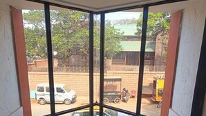Ein Zimmer mit großen Fenstern, die auf einen Innenhof mit Pool, ein Auto und ein Motorrad blicken.