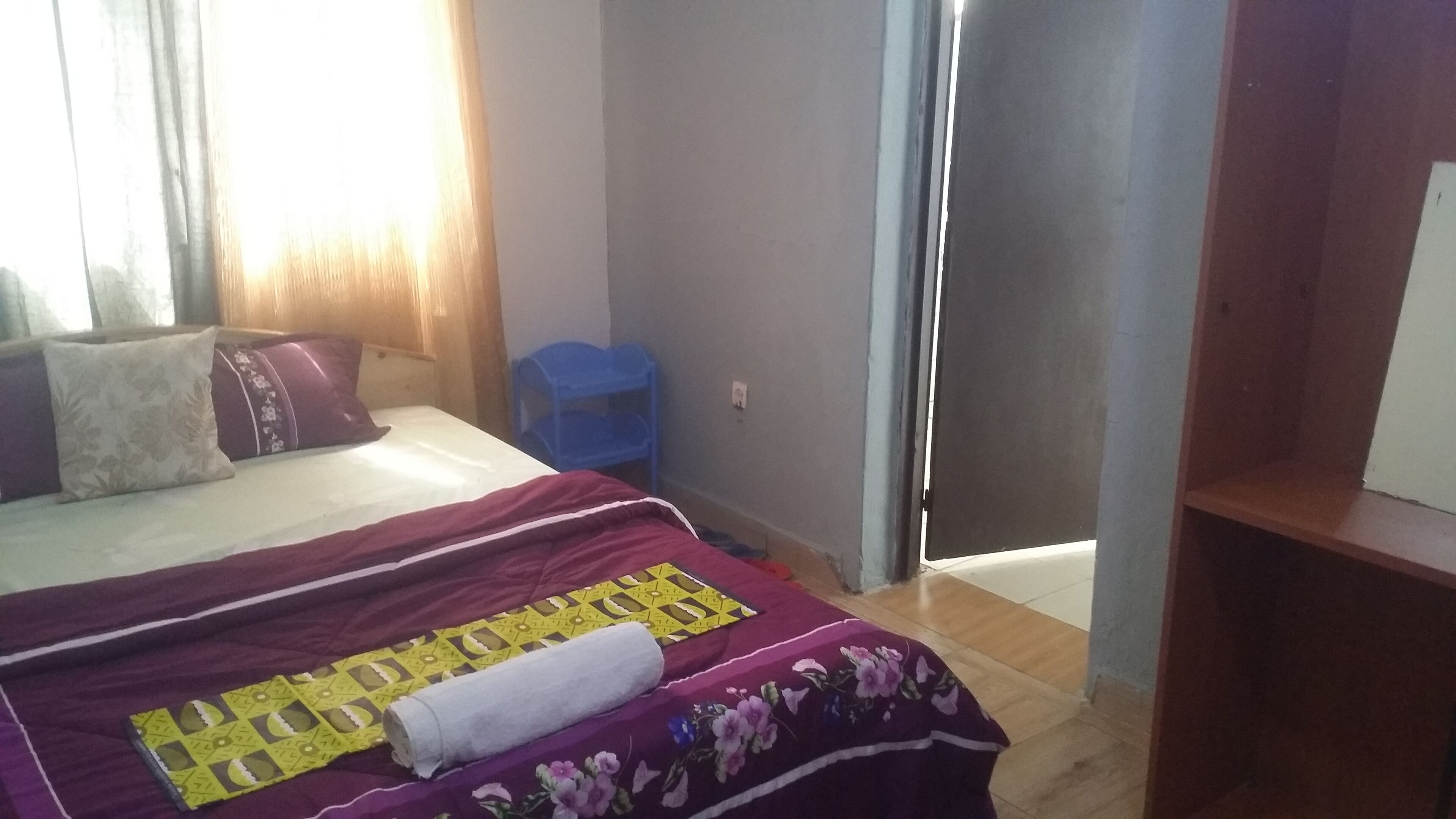 Un dormitorio con una cama, una silla azul y un armario.