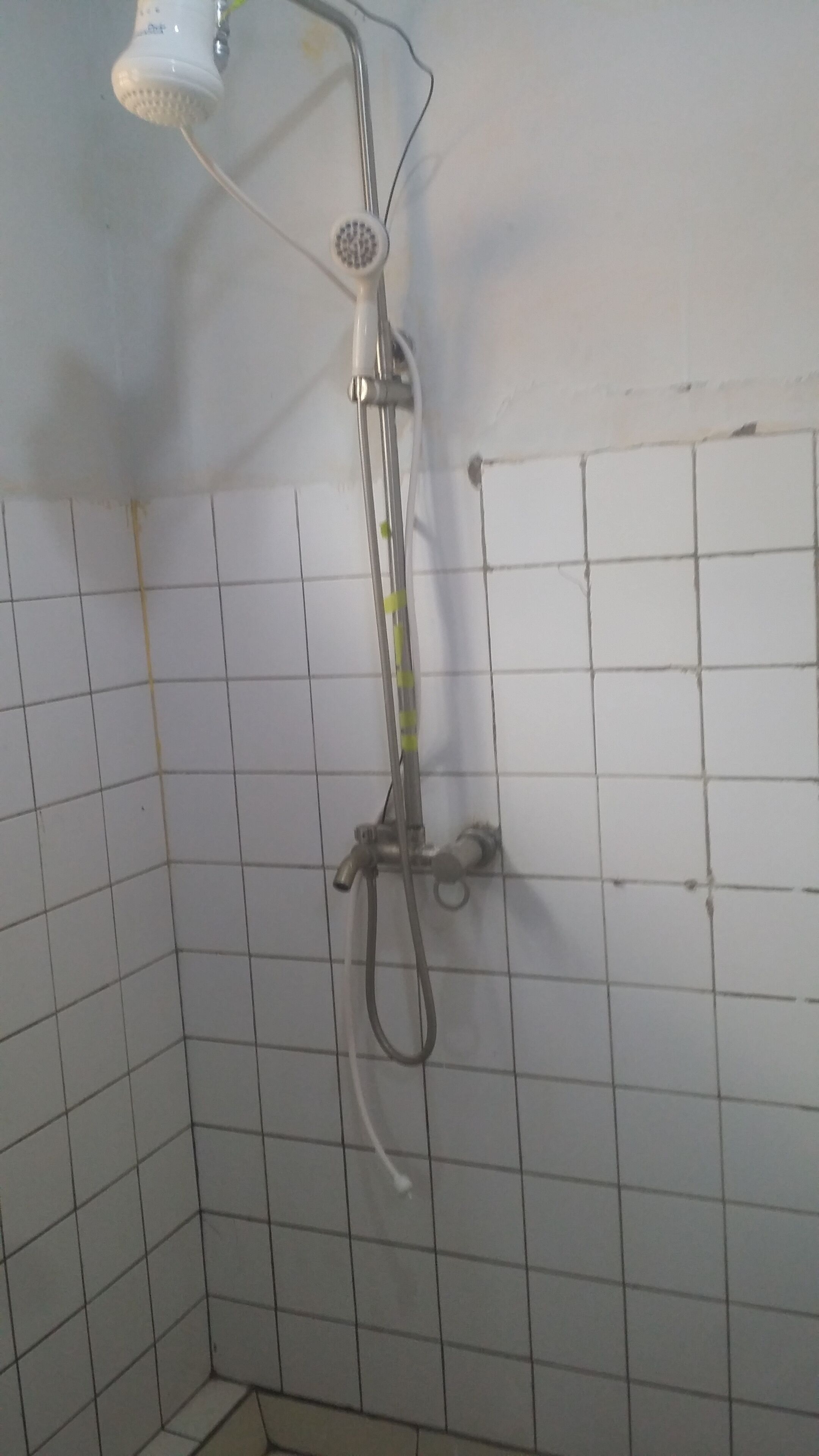 A shower with a handheld showerhead and a wall-mounted faucet.