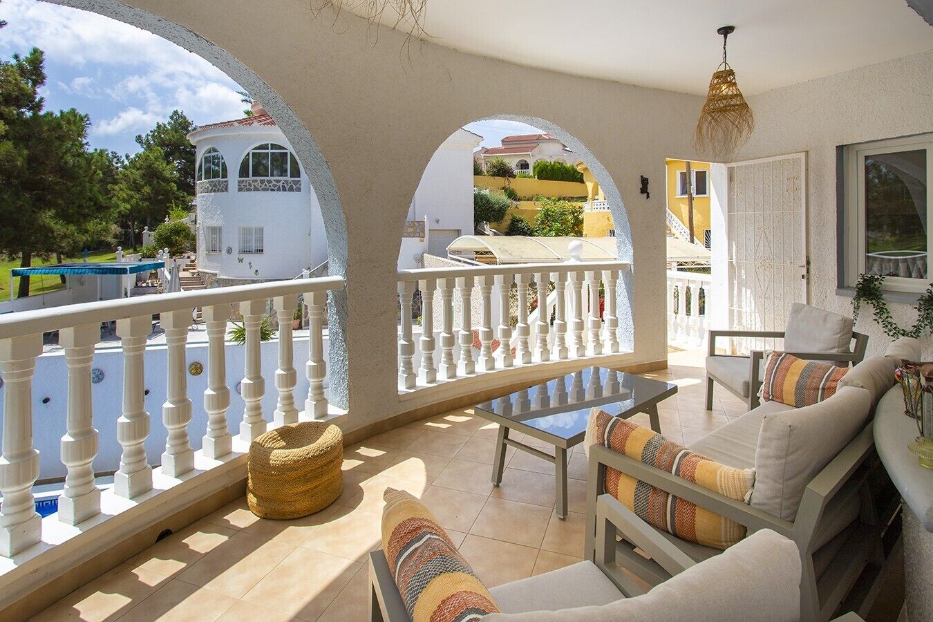 A balcony with a white balustrade, a wicker basket, and a sofa with cushions.