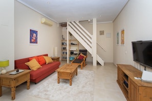 Ein Wohnzimmer mit einem roten Sofa, einem Holztisch und einem Fernseher auf einem Holzschrank.