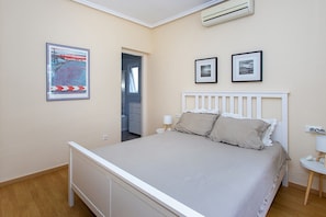 Ein Schlafzimmer mit einem Bett, einem Nachttisch, einer Lampe und einer Wand-Klimaanlage.