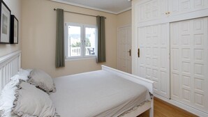 A bedroom with a bed, a window with curtains, a wardrobe, and a radiator. - CH Villa Golf Park La Marquesa Golf (Ciudad Quesada) (Ciudad Quesada)