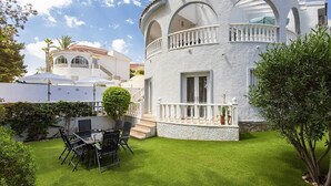 A white building with a balcony, a small garden with artificial grass, and a table with chairs. - CH Villa Golf Park La Marquesa Golf (Ciudad Quesada) (Ciudad Quesada)