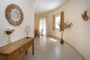 A hallway with a wooden bench, a mirror, a vase with flowers, a lamp, and a window with curtains. - CH Villa Golf Park La Marquesa Golf (Ciudad Quesada) (Ciudad Quesada)