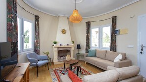 Una sala de estar con chimenea, sofás, televisor y comedor.