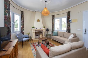 Een woonkamer met een open haard, banken, een televisie en een eethoek.