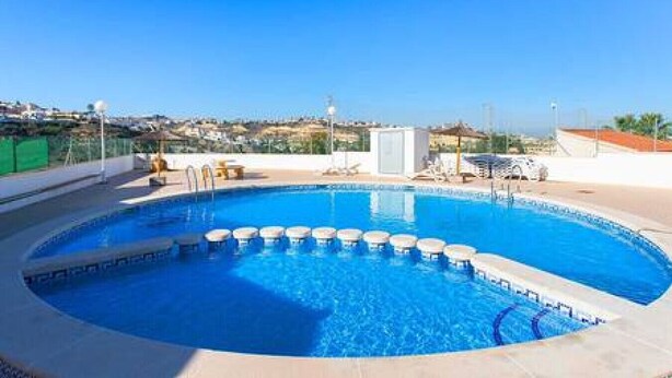 A rooftop swimming pool with a clear view of the city in the background.