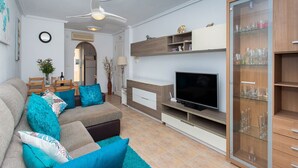 A living room with a sofa, TV, and glass cabinet.