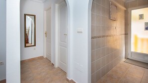 A hallway with white walls, a tiled floor, and a door with a mirror.