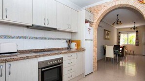 A kitchen with white cabinets, a microwave, and an oven. There is a dining area with a table and chairs.