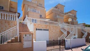 A residential building with multiple balconies, a gated entrance, and a staircase leading to the upper floors.
