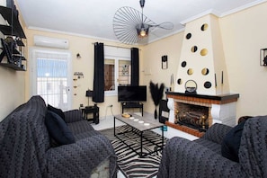 A living room with a fireplace, a television, and a ceiling fan.