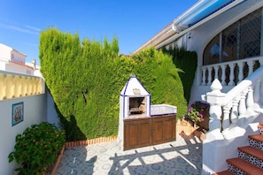 A courtyard with a small wooden structure, a white staircase, and a neatly trimmed hedge.
