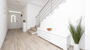 Een modern interieur met een trap, witte kasten en een plant.