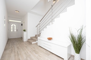 Ein modernes Interieur mit Treppe, weißen Schränken und einer Pflanze.