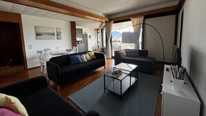 A modern living room with a sofa, coffee table, and a dining area with chairs and a table. - Lugano City Apartment in Cassarate facing the lake, 5min from the centre (Lugano)