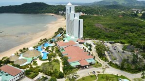 Un complexe hôtelier doté d’une plage, d’un grand bâtiment avec une tour et d’un espace piscine.
