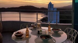 A dining table with bowls of food and drinks, set against a scenic sunset view. - Luxury Paradise at Playa Bonita (Panama City)