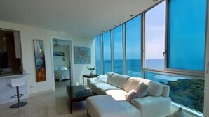 A modern living room with a large window, a white sofa, and a coffee table. - Luxury Paradise at Playa Bonita (Panama City)