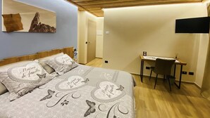 A bedroom with a bed, a desk, and a TV mounted on the wall. - Bed and Breakfast Soffio di Vento (Perloz)