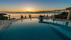A swimming pool with a view of the sunset and mountains.
