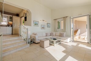 A spacious living area with a sofa, coffee table, and staircase leading to a kitchen.