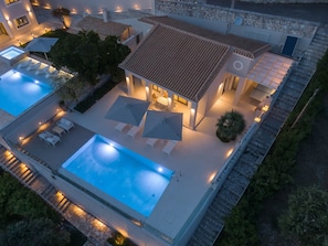 Ett modernt hus med en swimmingpool, utomhusmöbler och en fasad av sten.
