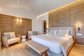 Un dormitorio moderno con una cama grande, un banco, un sofá y una pared de acento de madera.