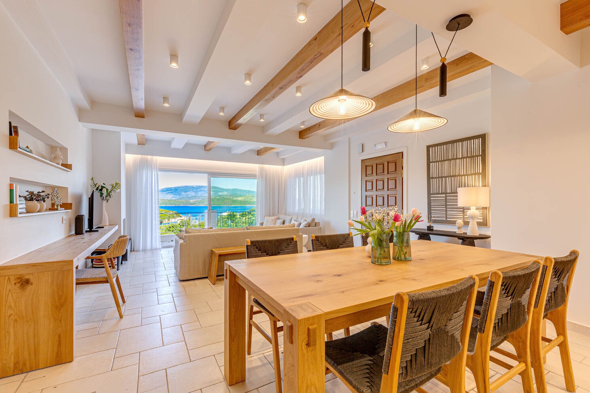 A spacious living area with a wooden dining table, wicker chairs, and a view of the outdoors.