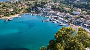 A coastal town with a marina, houses, and hilly terrain. - Agios Stefanos Bay - Villa Maria (Agios Stefanos Kassiopi)