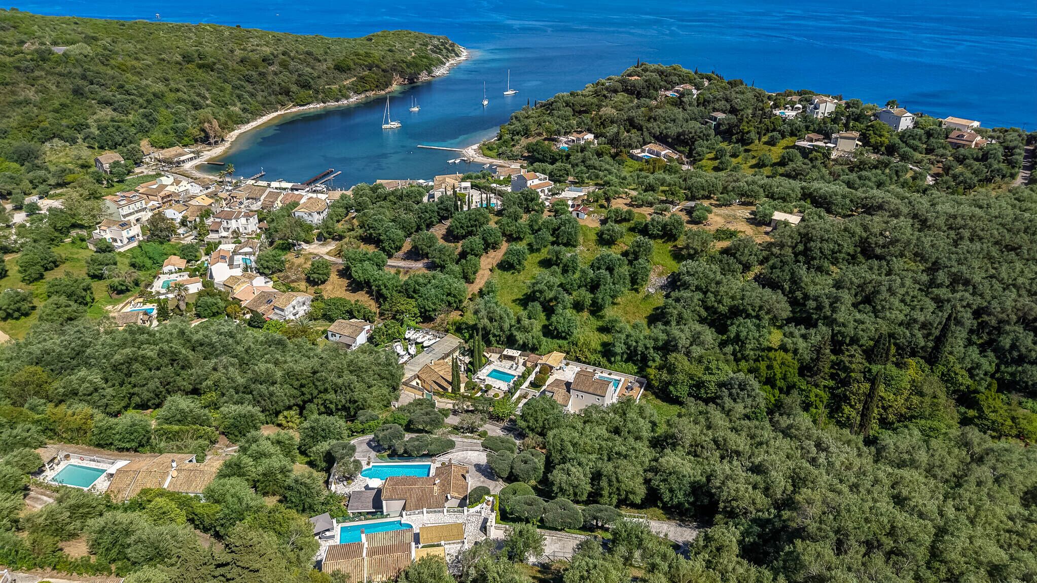 An aerial view of a coastal area with houses, a marina, and a swimming pool.
